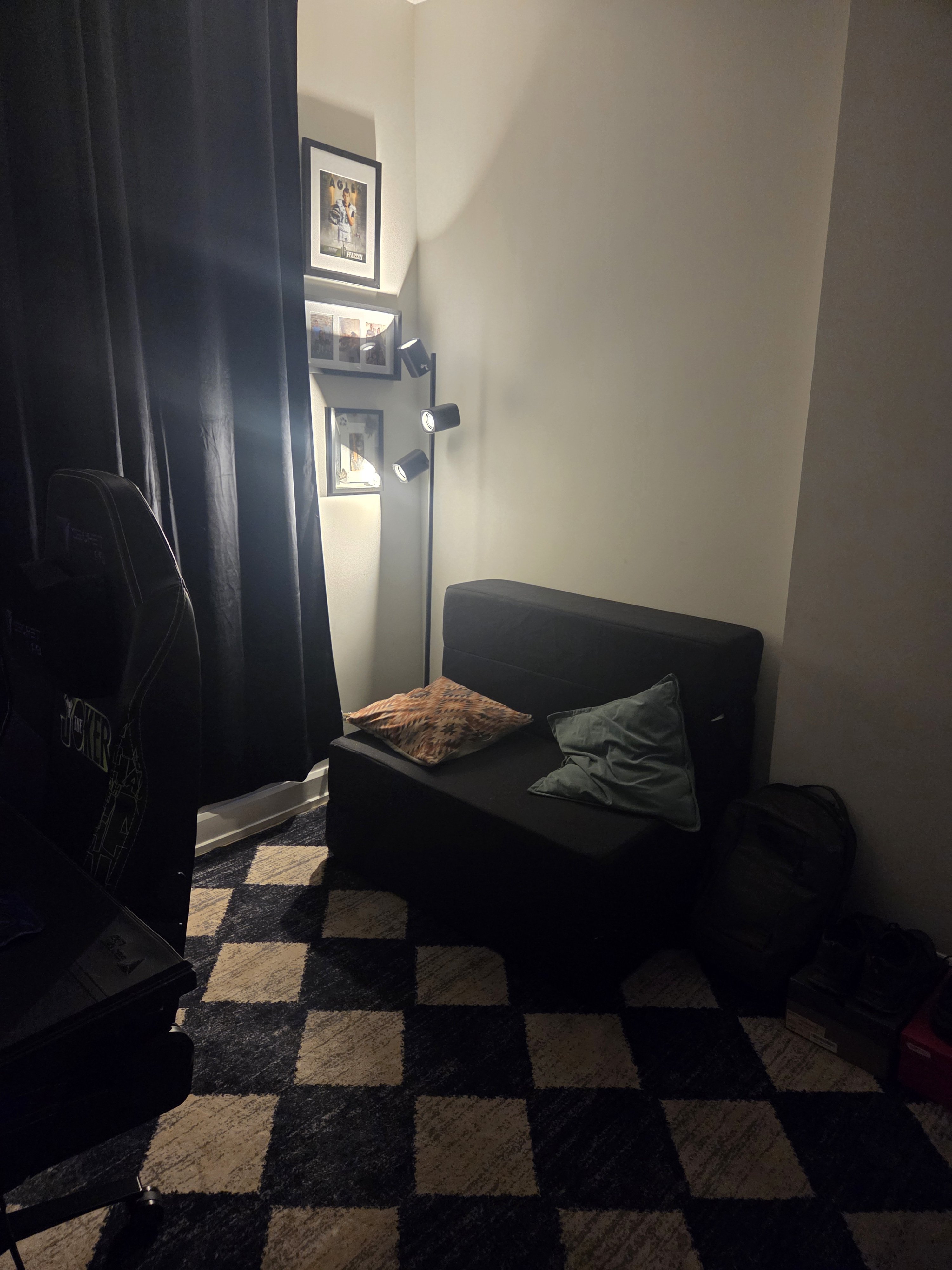 The reading nook — chair, pillows, the new floor lamp lighting the photo wall.